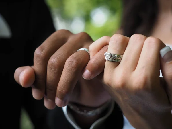 Encerramento de um casal com anéis de casamento segurando as mãos com um fundo borrado — Fotografia de Stock