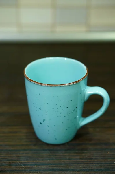 Tiro de close-up vertical de um copo de cerâmica azul claro em uma superfície de madeira — Fotografia de Stock