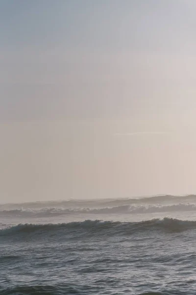 Tiro vertical das ondas do mar sob um céu nublado — Fotografia de Stock