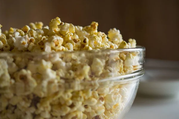 Detailní záběr popcornu ve skleněné misce s rozmazaným pozadím — Stock fotografie