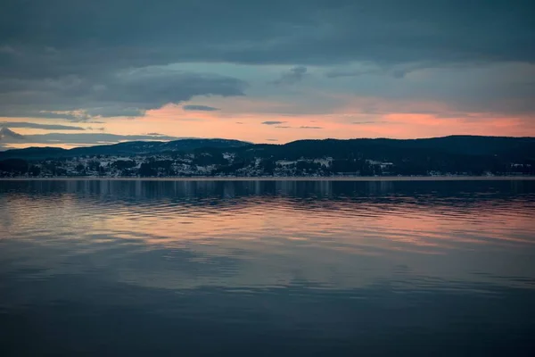 Schöne Landschaft des Sonnenuntergangs, die sich auf dem Meer spiegelt, umgeben von hohen felsigen Bergen — Stockfoto