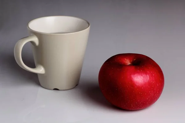 Gros plan minimaliste d'une tasse blanche et d'une pomme rouge — Photo