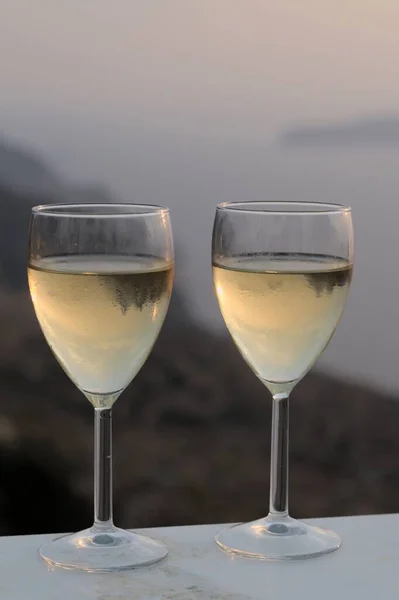 Tiro romántico vertical de copas de vino blanco en una noche de verano en la isla griega de Sikinos — Foto de Stock