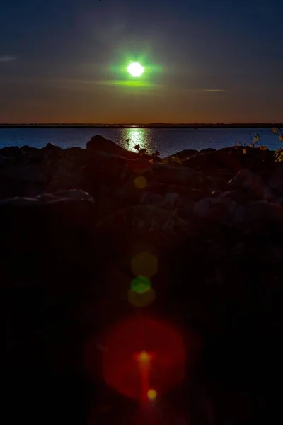 Mar cercado por rochas e vegetação durante um belo pôr do sol com um efeito bokeh — Fotografia de Stock