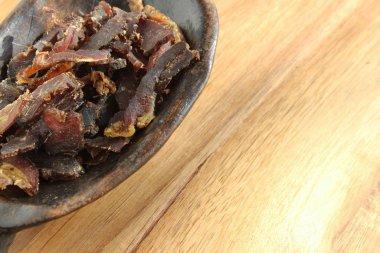 A bowl filled with traditional South African biltong on a wooden surface clipart