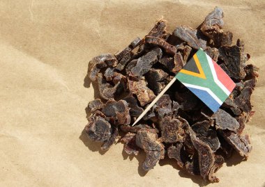 The flag of South Africa on traditional biltong snack on a wooden surface clipart