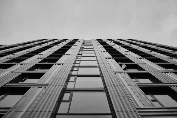 Baja escala de grises de un rascacielos moderno bajo el cielo nublado. —  Fotos de Stock