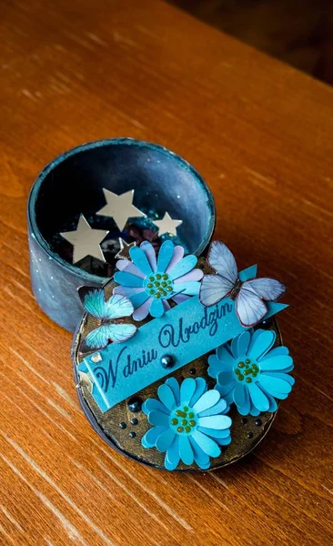 Vue en haut des fleurs bleues, des papillons et des étoiles dans un contenant sur une table — Photo