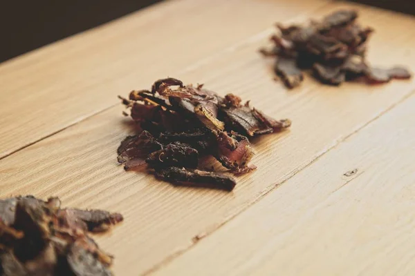 A wooden surface with a lot of chopped biltong snacks