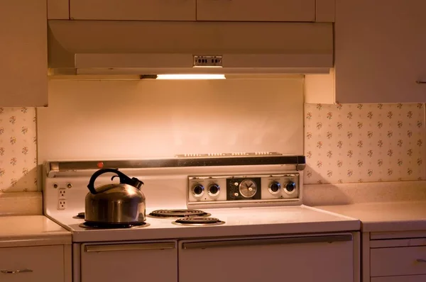Estufa de gas con una olla en la cocina rodeada de armarios bajo las luces —  Fotos de Stock