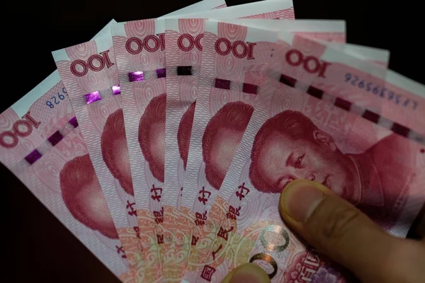 Primo piano di una persona che tiene Yuan cinese di fronte a uno sfondo nero — Foto Stock