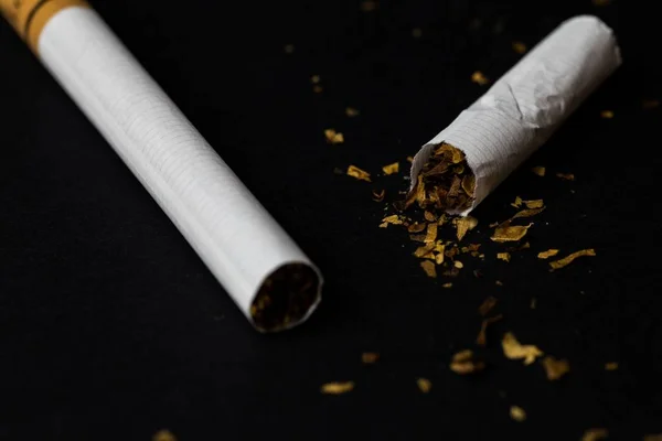 Avvicinamento di una sigaretta tagliata a metà fumata — Foto Stock
