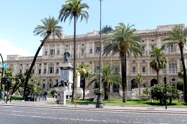 Straat omringd door palmbomen gebouwen en standbeelden onder het zonlicht in Rome in Italië — Stockfoto