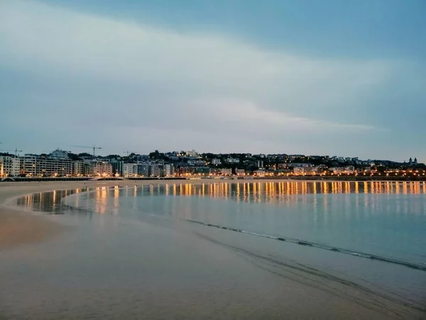 スペイン セバスティアンの海を反射する街の光の魅惑的な夜の風景 — ストック写真