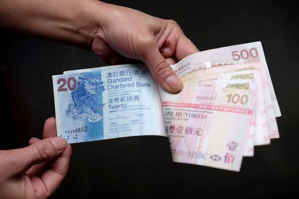 Primo piano di una persona che detiene Singapore dollari di fronte a uno sfondo nero — Foto Stock