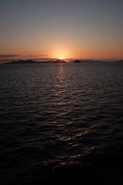 Paesaggio del mare circondato da rocce durante il tramonto con il sole che si riflette sull'acqua — Foto Stock