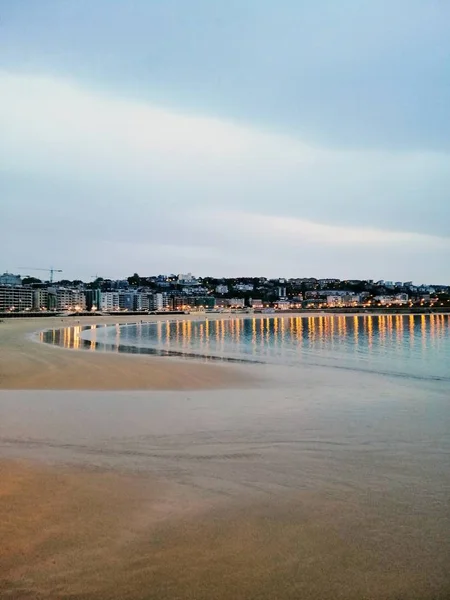 Vertical Shot Mesmerizing Evening Scenery Town Lights Reflecting Ocean San — 스톡 사진