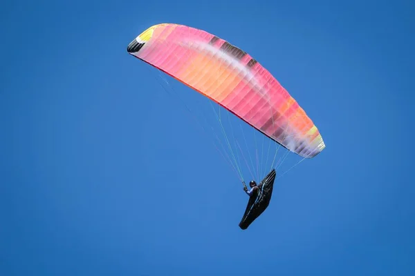 Tiefflug einer Person beim Gleitschirmfliegen an einem sonnigen Tag unter hellem Himmel — Stockfoto