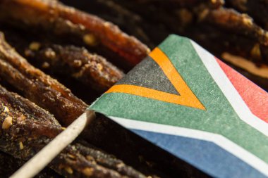 The flag of South Africa on traditional biltong snack on a wooden surface clipart