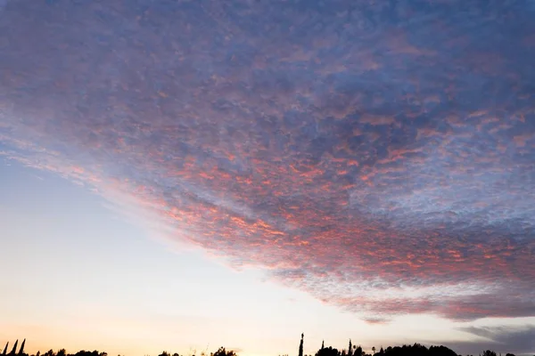 Bonito tiro de nuvens brancas em um céu azul claro com paisagem de nascer do sol — Fotografia de Stock