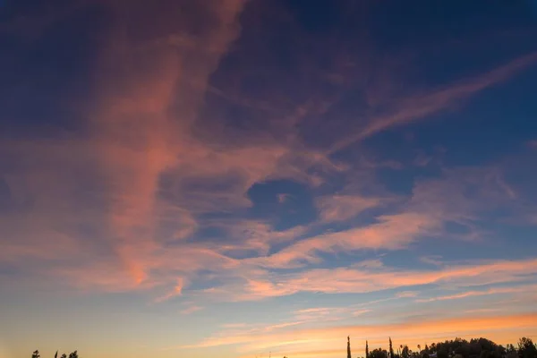 Bonito tiro de nuvens cor de rosa em um céu azul com cenário de nascer do sol — Fotografia de Stock