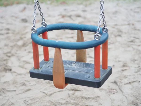 Hoge hoek close-up shot van een schommel voor kleine kinderen met een zanderige grond onder — Stockfoto