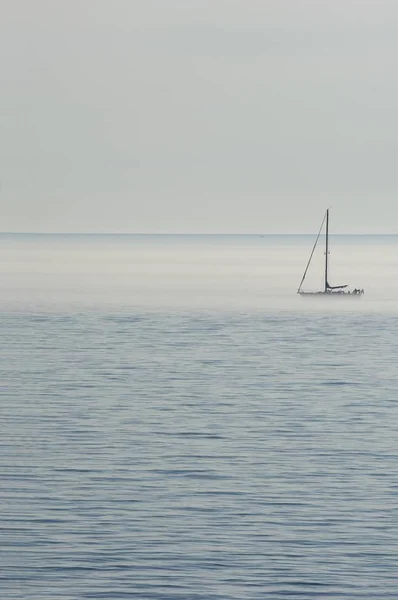 Κάθετη εικόνα της θάλασσας με ένα πλοίο πάνω της καλυμμένο με ομίχλη κάτω από ένα συννεφιασμένο ουρανό — Φωτογραφία Αρχείου