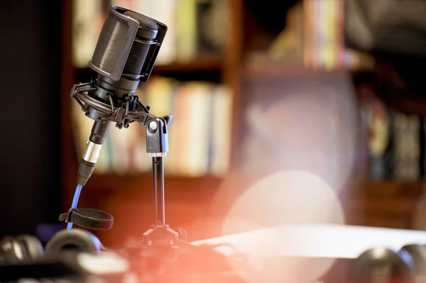Micrófono en un estudio rodeado de equipo bajo las luces con un fondo borroso —  Fotos de Stock