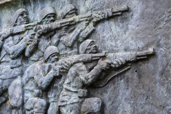 Closeup of a stonewall carving of soldiers holding guns — Stock Photo, Image