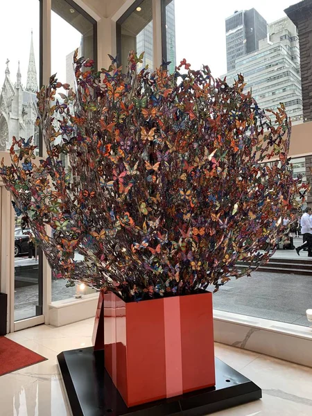 Vertikal bild av en vacker skulptur med många fjärilar på grenarna i en vas — Stockfoto