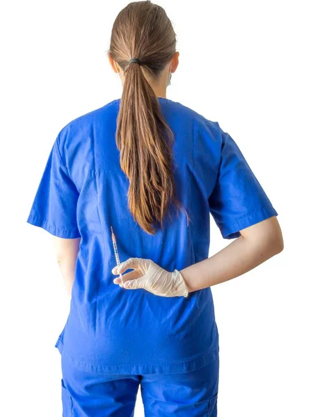 Doctora en un uniforme médico azul con guantes esterilizados con una jeringa detrás de la espalda. — Foto de Stock