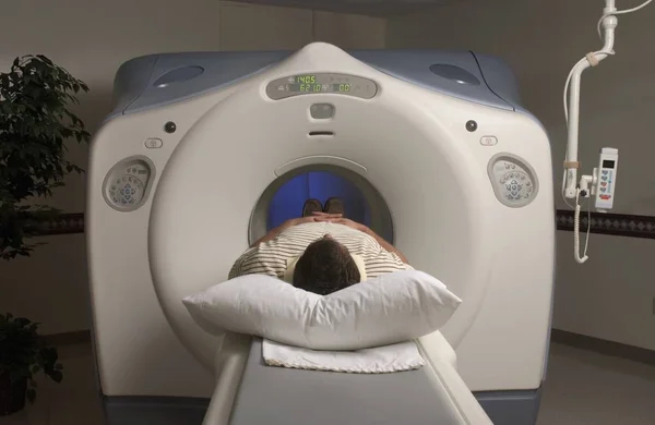 Pessoa deitada em um scanner de RM sob as luzes de um hospital — Fotografia de Stock