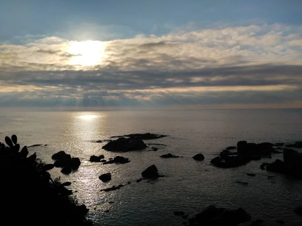 Aufnahme des Ozeans unter dem wolkenverhangenen Himmel während des Sonnenuntergangs — Stockfoto