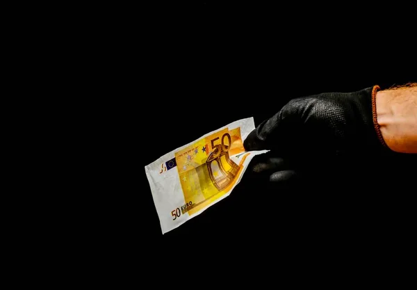 Paysage d'un homme portant des gants noirs tenant un billet de 50 euros avec un fond noir — Photo