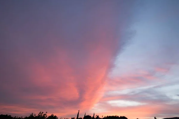 Bonito tiro de nuvens cor de rosa em um céu azul claro com uma paisagem de nascer do sol — Fotografia de Stock