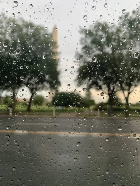 Encerramento vertical disparado de gotas de água sobre o vidro e árvores desfocadas no fundo — Fotografia de Stock