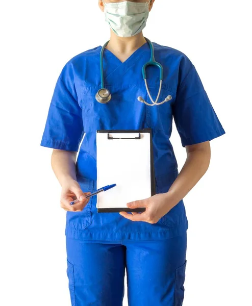 Médico fêmea novo em um uniforme médico azul apontando para um papel branco em branco com um espaço de cópia — Fotografia de Stock