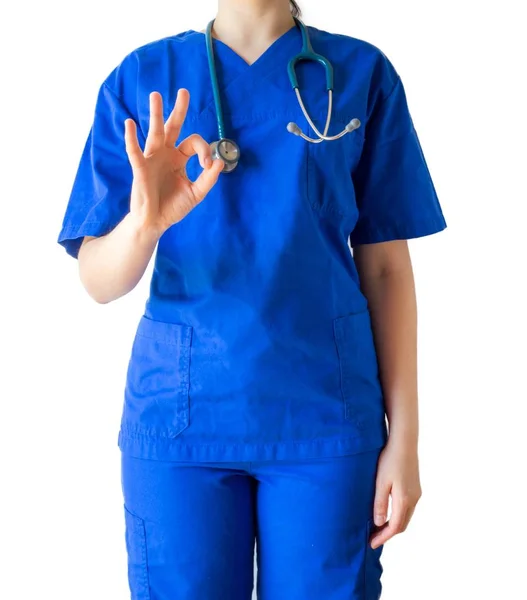 Médico feminino bem sucedido em um uniforme médico azul mostrando sinal ok isolado em um fundo branco — Fotografia de Stock