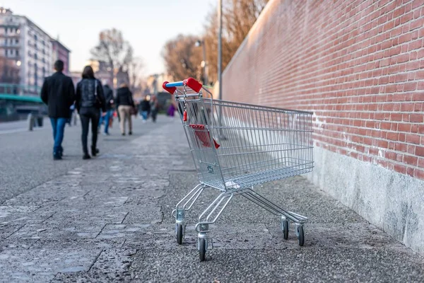 Mělké zaostření záběru nákupního vozíku umístěného na chodníku s rozmazaným pozadím — Stock fotografie