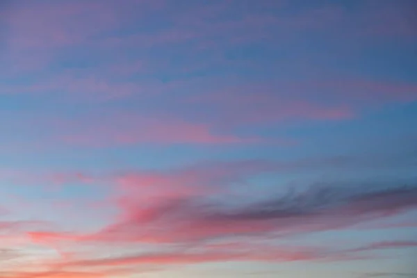 Bonito tiro de nuvens cor de rosa em um céu azul com uma paisagem de nascer do sol — Fotografia de Stock