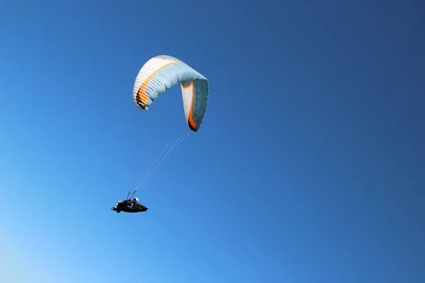 Low angle shot of a person paragliding on a sunny day under the bright sky — Stock Photo, Image