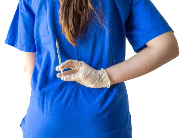 Médico feminino em um uniforme médico azul com luvas esterilizadas segurando uma seringa atrás de suas costas — Fotografia de Stock
