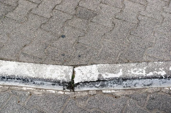 Closeup shot of the edge of a sidewalk with grey concrete tiles — Stock Photo, Image