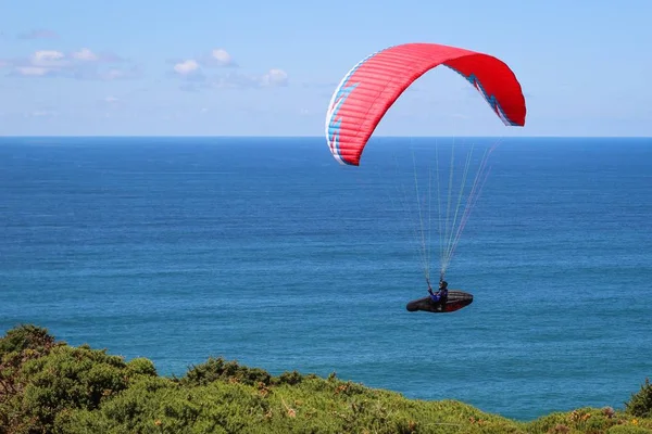 Gleitschirmfliegen an einem sonnigen Tag mit dem ruhigen Meer im Hintergrund — Stockfoto