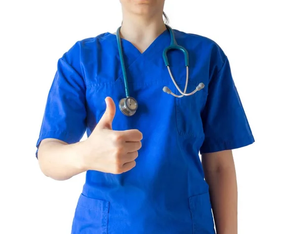 Ung kvinnlig läkare i en blå medicinsk uniform visar en tummen upp gest — Stockfoto