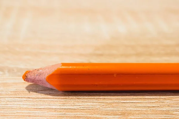 Encerramento tiro de um lápis de desenho laranja em uma superfície de madeira — Fotografia de Stock