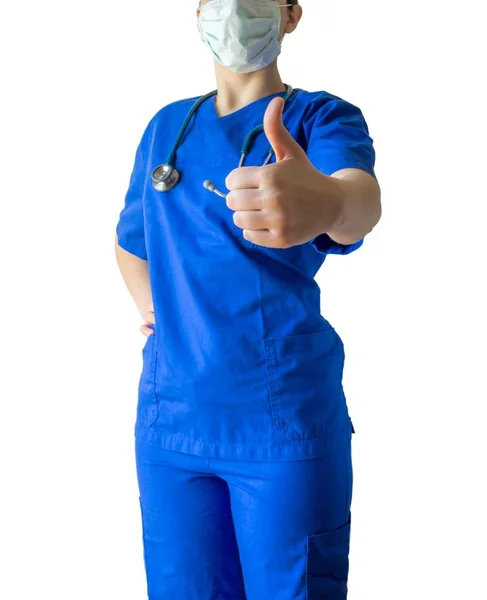 Una joven doctora caucásica que usa un uniforme médico azul y una máscara que muestra un pulgar hacia arriba. — Foto de Stock