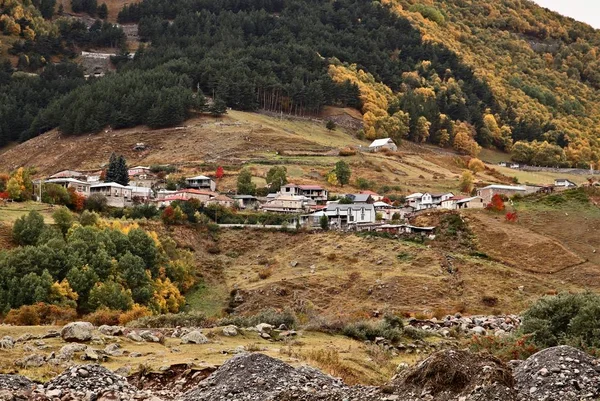 Scatto aereo di un villaggio circondato da montagne durante l'autunno — Foto Stock