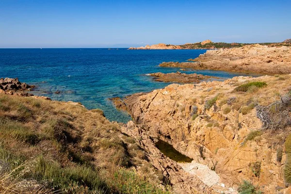 Landschapsopname van rotsachtige heuvels in een open blauwe oceaan met een heldere blauwe lucht — Stockfoto