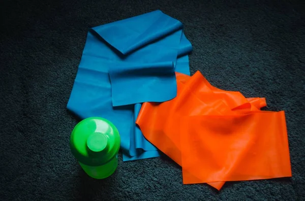 Kopfschuss einer Wasserflasche in der Nähe eines blauen und roten Gummis auf dem Boden — Stockfoto